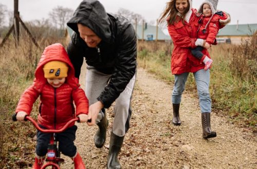 Family enjoying a joyful autumn walk along a rustic dirt road in vibrant outfits.
