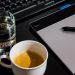 Office desk setup with a coffee cup, glass of water, tablet, pen, and keyboard.